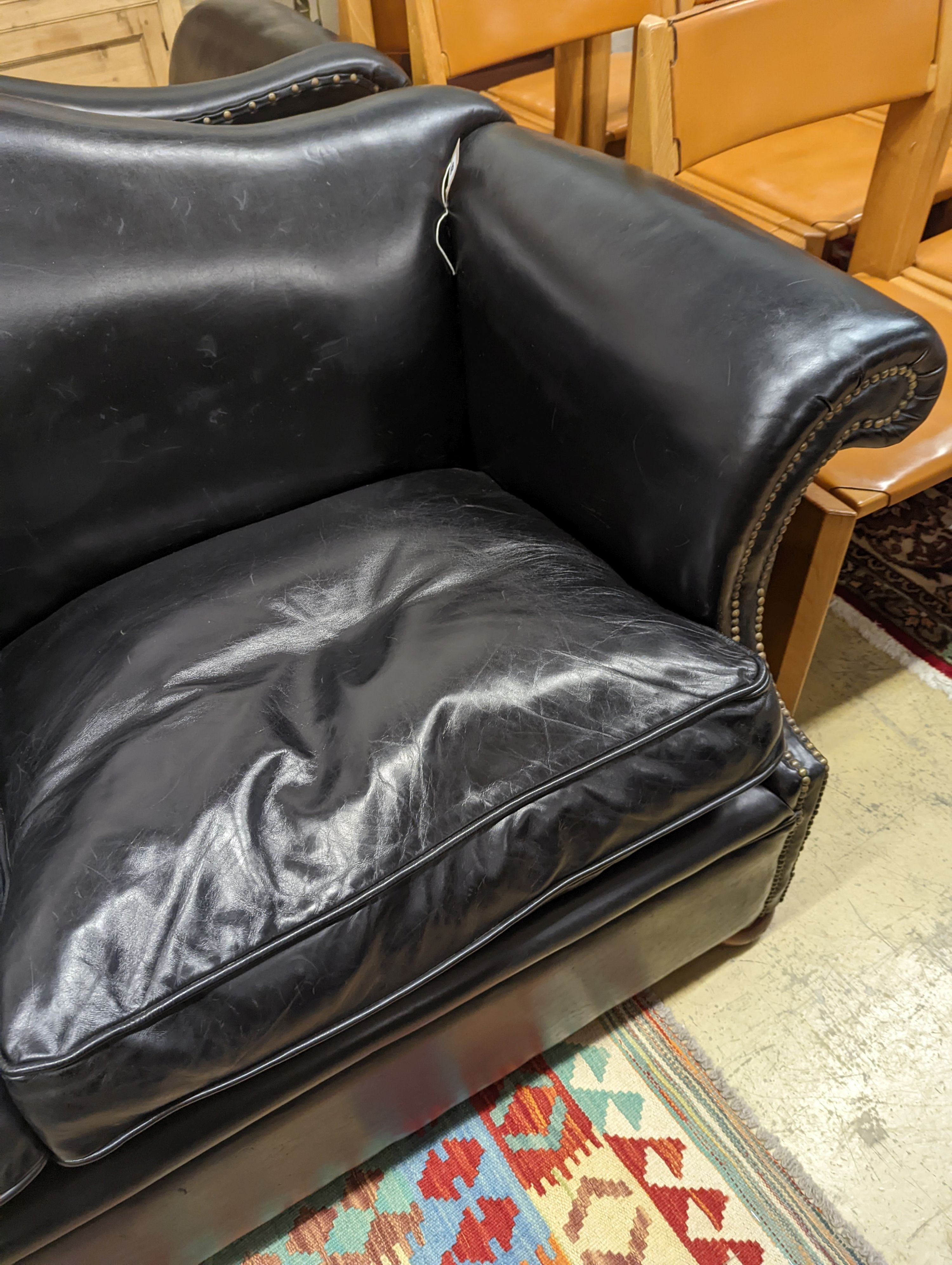 A pair of black leather scroll arm two seater settees on flat bun feet, length 184cm, depth 80cm, height 93cm